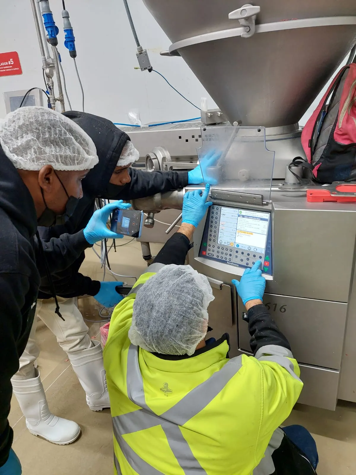 IDEINCA technicians adjusting a filling machine at a client's plant